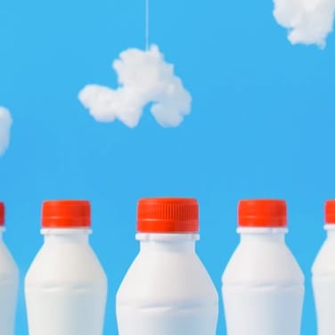 Milk bottles with a design of a blue sky with some clouds behind them